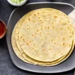 A plate of cactus tortillas. The tortillas are warm and slightly charred, and are placed neatly on a plate.